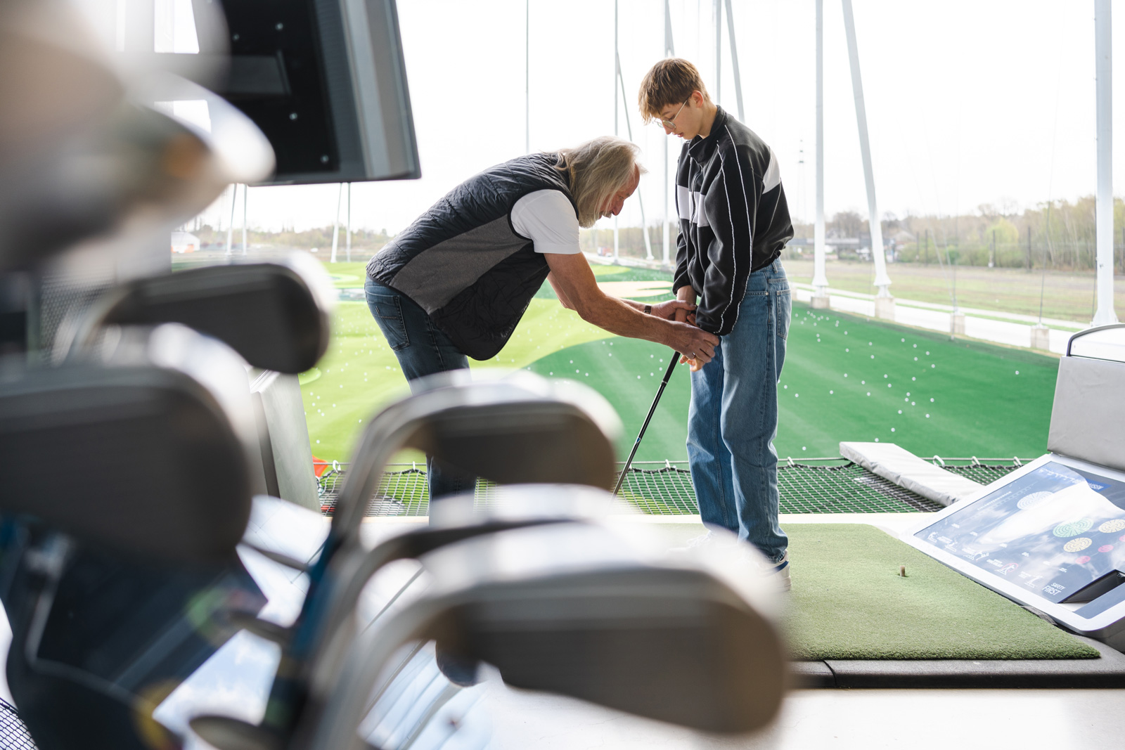 Jeune golfeur qui reçoit les conseils d’un coach sur la bonne position à prendre avant de s’élancer.