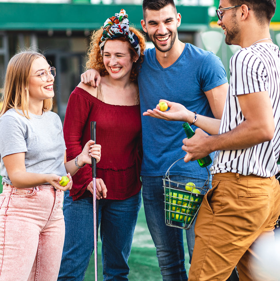 Quatre amis discutent et sourient, bâtons et balles de golf à la main.